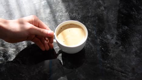 将一杯白色咖啡放在黑色大理石桌上